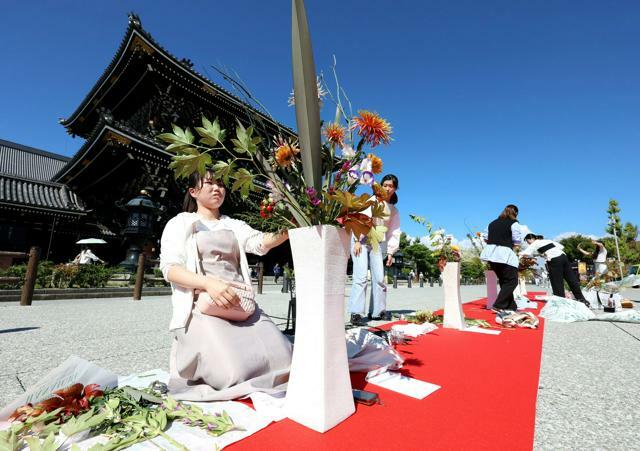 東本願寺前で、生け花の制作に挑む会員ら=2024年10月12日午前、京都市下京区、新井義顕撮影