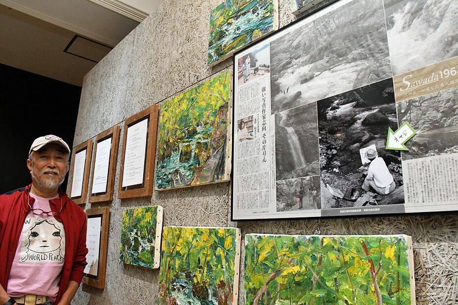 父・國春さんが写った沢田の写真を前にする和春さん。一緒に飾られた絵は、國春さんが好んで描いた奥入瀬渓流の油絵