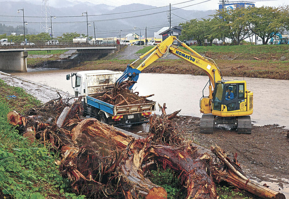 流木の除去作業を行う作業員＝４日午前１０時２０分、輪島市河井町の河原田川