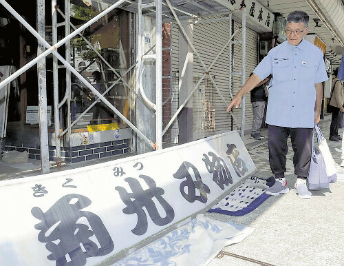 「心の荷が下りた」と看板を見つめる高橋さん（１３日、沼津市で）