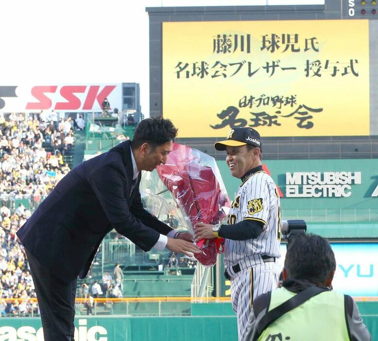 名球会ブレザー授与式で岡田監督から花束を受け取る藤川球児氏（左）＝2023年5月、甲子園球場