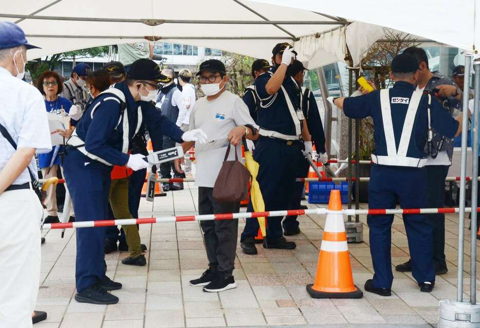 金属探知機で検査する警備担当者＝１９日、鹿児島市のＪＲ鹿児島中央駅東口駅前広場