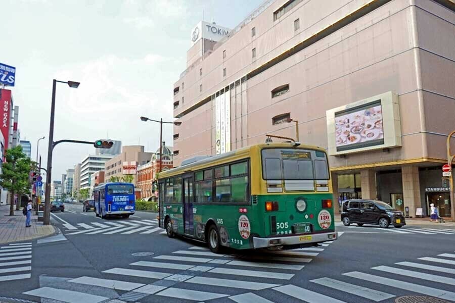 トキハ百貨店前、かつての軌道跡を走る大分交通バス。別大電車のラッピングがなされている。大分交通は現在も豊州電気鉄道が設立された1896年8月5日を創業日としている（画像：若杉優貴）