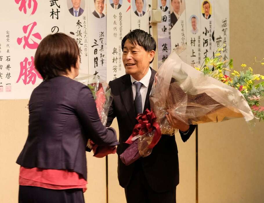 5選が確実となり、支援者から花束を受け取る武村展英氏＝滋賀県草津市