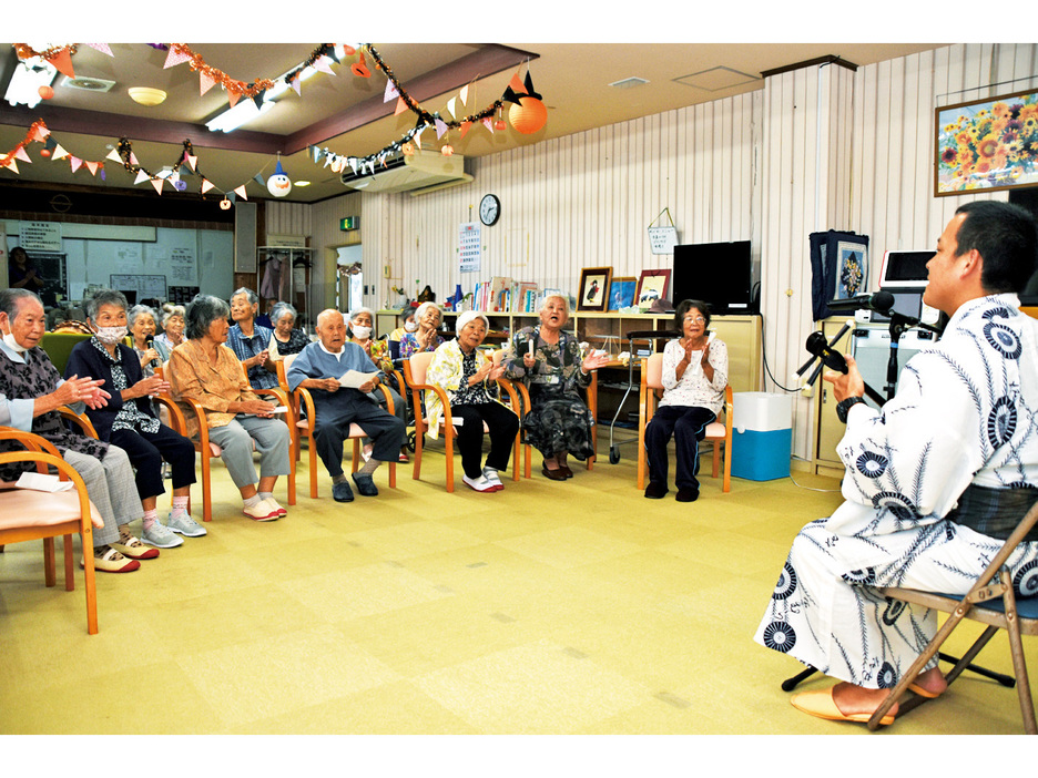 内山耕太郎さん（右）がデイサービス利用者に島唄などを披露し盛り上がった大和村社会福祉協議会のミニコンサート＝17日、大和村