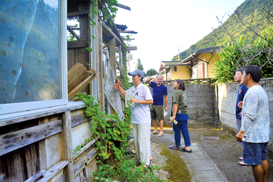 廃屋となっている空き家を調査するあまみ空き家ラボの専門家と名音集落住民ら＝12日、鹿児島県大和村名音