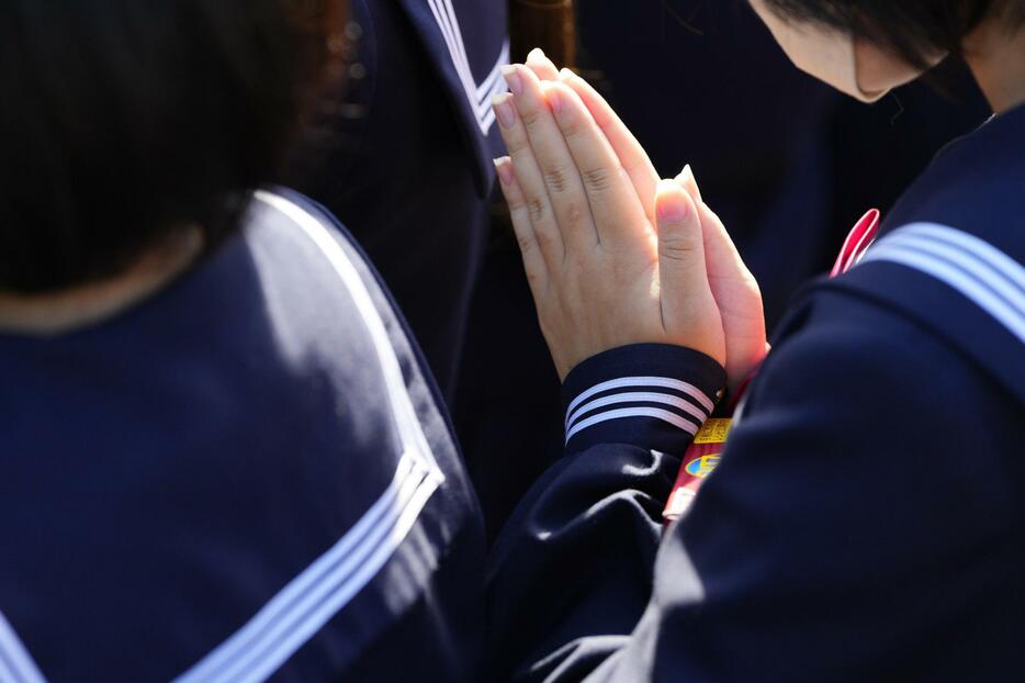 喜三翼音さんの葬儀に参列し、手を合わせる生徒＝12日午前、石川県輪島市