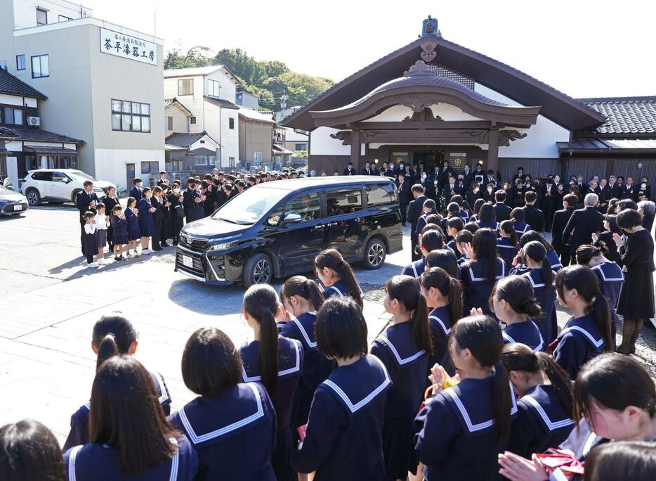 喜三翼音さんの父鷹也さんらを乗せ、葬儀会場を出る車を見送る多くの参列者＝12日午前、石川県輪島市