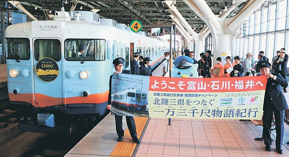 ホームで横断幕を掲げて参加を歓迎する関係者＝富山駅