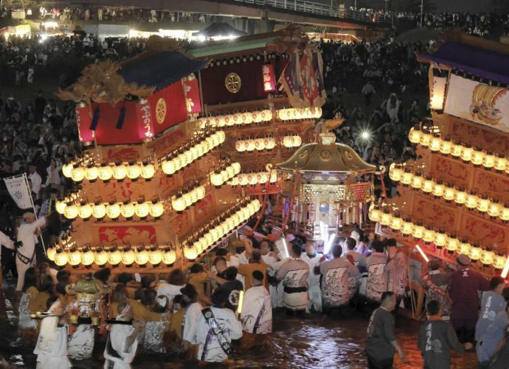 伊曽乃神社祭礼の「川入り」で、行く手を阻むだんじりの間を縫って進む神輿＝16日午後6時10分ごろ、西条市の加茂川