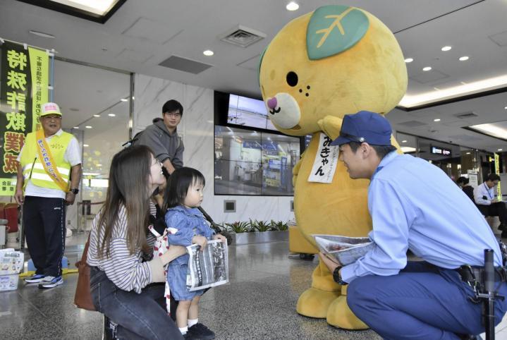 空港利用者に特殊詐欺などへの注意を呼びかける松山西署員とみきゃん＝11日午前、松山空港到着ロビー