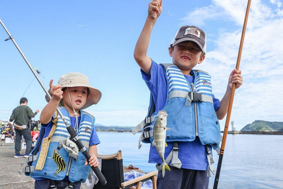 魚を釣り上げて笑顔を見せる子ども（２０日、和歌山県串本町串本で）