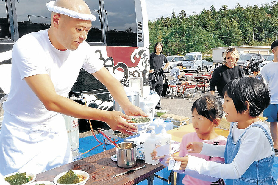 ラーメンを手渡すあばれる君＝七尾市能登島向田町