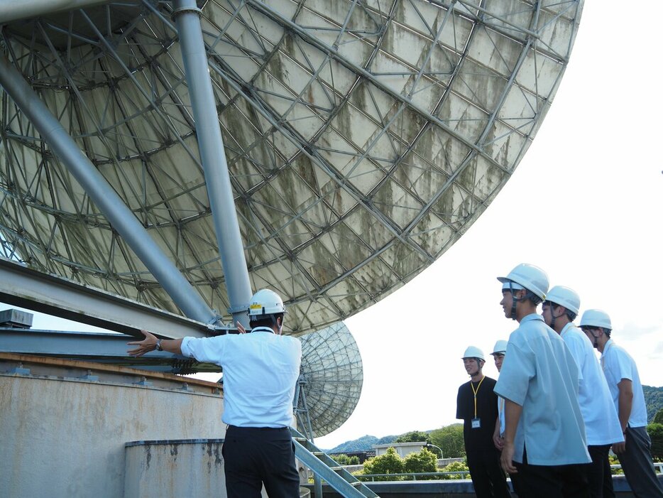 山口県にあるKDDIのパラボラアンテナの前でインターンに参加する学生たち。出身学部は多岐にわたり、宇宙に興味のある学生も入社している（写真：KDDI提供）