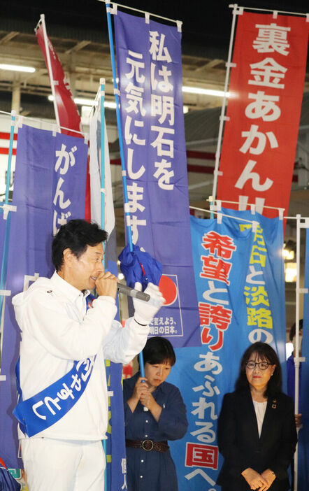 衆院選ラストデーに、JR明石駅で最後の演説を行った無所属出馬の前職・西村康稔氏（左）の背後には「裏金あかん！！」の旗も。右は丸谷聡子・明石市長（カメラ・筒井政也）