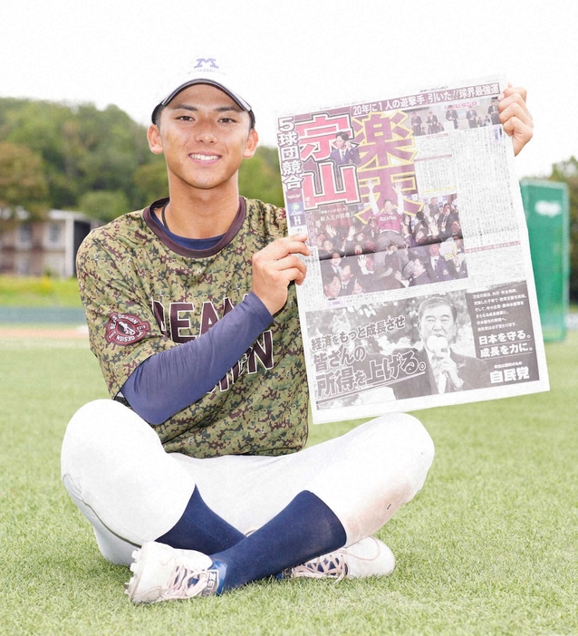 自身が楽天に1位指名されたことを報じる本紙を手に笑顔の明大・宗山（撮影・木村　揚輔）　