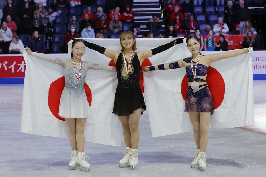 日の丸を掲げる優勝した坂本花織（中央）と2位の松生理乃（左）、3位の吉田陽菜＝ハリファクス（共同）