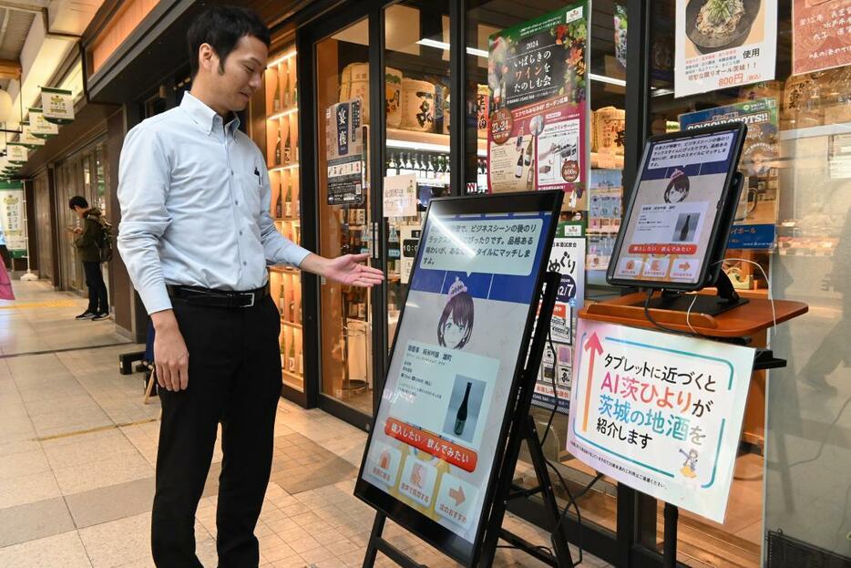 いばらき地酒バー水戸の店舗前で本県産の地酒を紹介するAI茨ひより=JR水戸駅コンコース