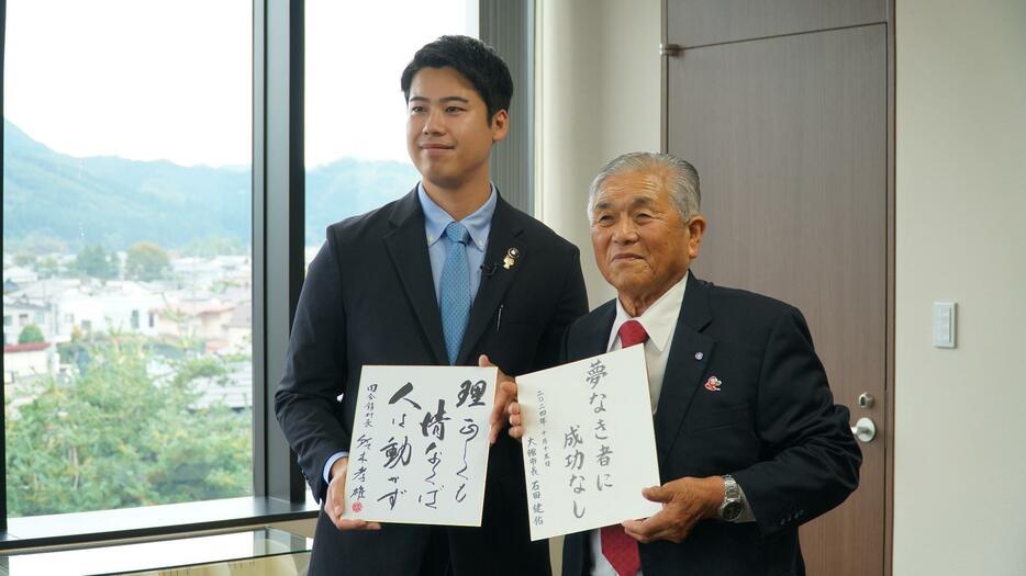 「座右の銘」を書いた色紙を交換した石田市長と鈴木村長