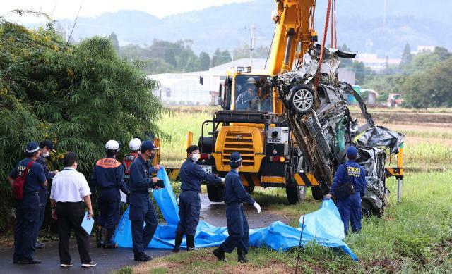 大雨で流されたとみられる軽自動車を引き上げる関係者ら＝２３日午前８時２５分、日南市東弁分