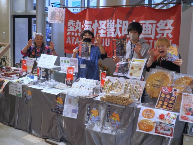 ユタゴンとのコラボ商品を並べ、横断幕を掲出してイベントをＰＲする催事ブース＝熱海市田原本町