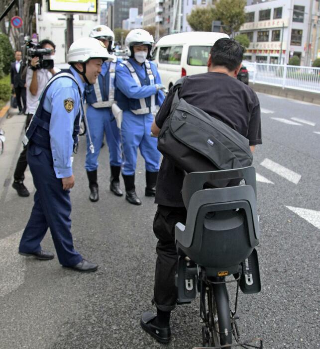 ながら運転と酒気帯びについて自転車利用者に注意喚起する警視庁の警察官ら＝10月25日、東京都中央区