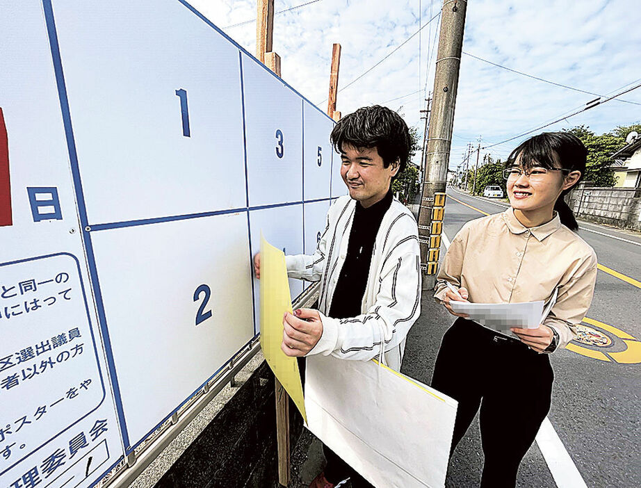 地図を手に掲示板を探し、候補者のポスターを貼る青島さん（左）と松浦さん＝15日、県内（写真の一部を加工しています）