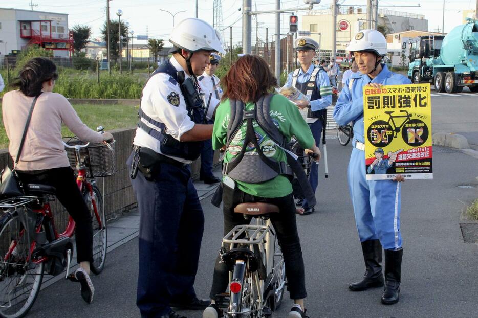 自転車走行中の携帯電話使用などに罰則を新設した改正道交法の施行を前に、新たなルールを周知する埼玉県警の警察官ら＝30日午後、埼玉県草加市