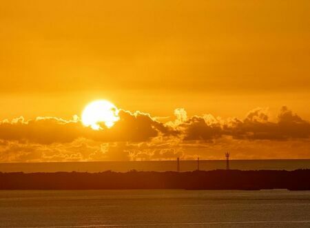 「神の島」と呼ばれる久高島越しに上る太陽。日の出の光を浴びると御利益がありそうです＝８日、南城市知念（銘苅一哲撮影）