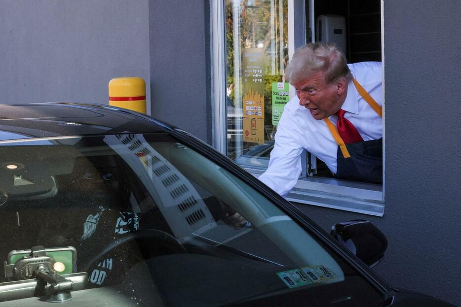 マクドナルドで商品を客に手渡すトランプ前大統領（ロイター）