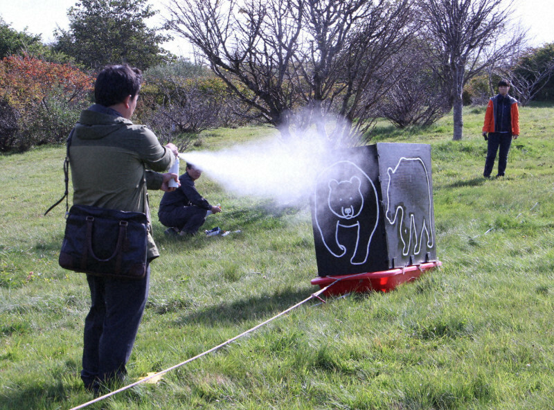 接近してくるヒグマに見立てた張りぼてに向かってクマ撃退スプレーを吹き付ける参加者＝根室市の市民の森で2024年10月8日午後1時15分、本間浩昭撮影