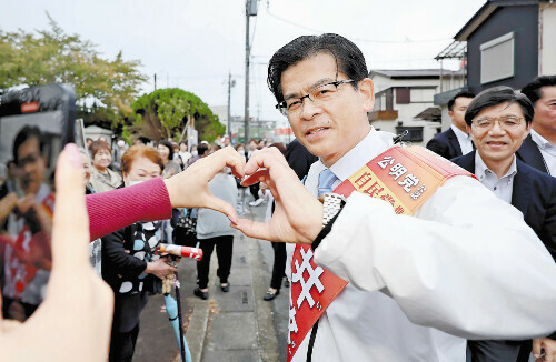 手でハートマークを作って撮影に応じる公明党の石井代表（１８日、埼玉県三郷市で）