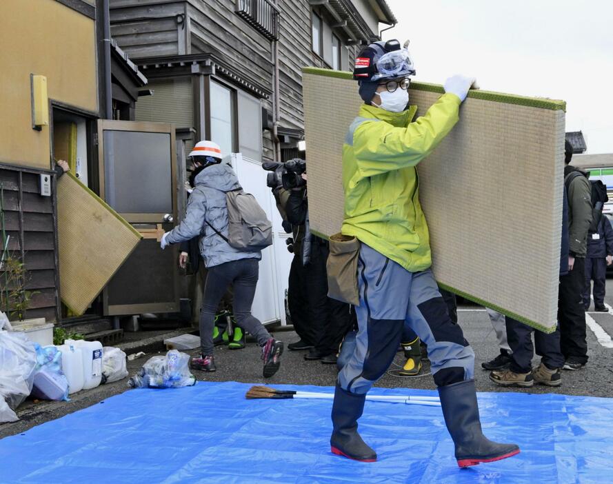 能登半島地震で被災した旅館から、ぬれた畳を運び出すボランティア＝2月、石川県輪島市