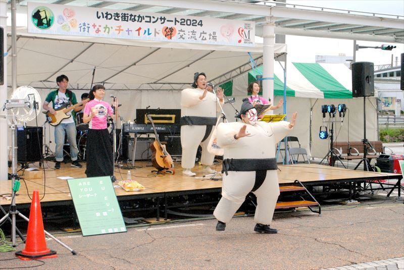 【力士姿】ポップスグループ「バンドになったシーザーサラダ」は、いわき駅前広場会場に登場。力士の着ぐるみ姿のメンバーが「どすこい」の掛け声を発しながら歌い、観客の笑いを誘った