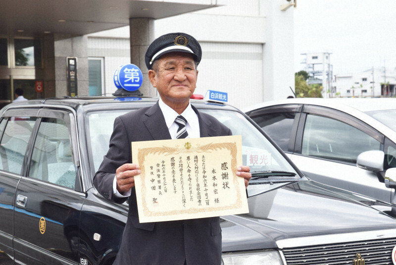 乗車するタクシーの前で感謝状を手にする水本和宏さん＝和歌山県白浜町の白浜警察署で2024年10月22日午後1時54分、大澤孝二撮影