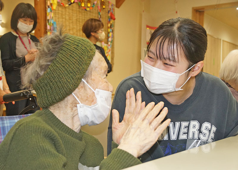 利用者（左）と目を合わせ、じっくり話を聞く専大北上福祉教育専門学校の学生