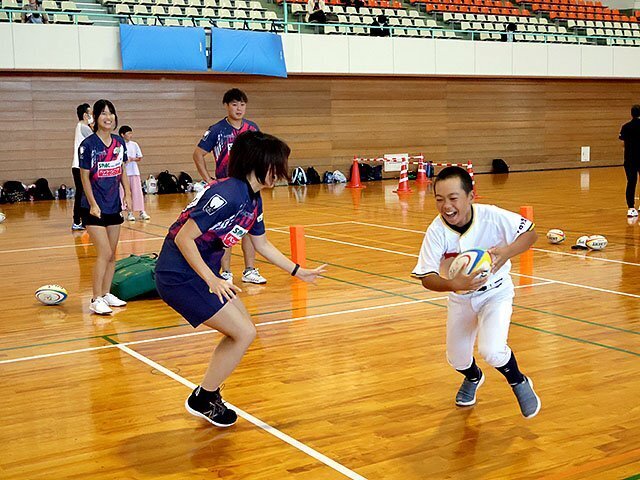 ラグビーボールを持って相手をかわす参加者