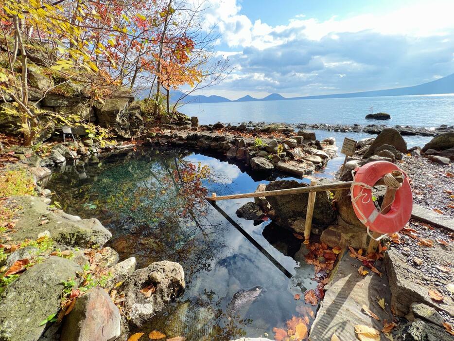 湯面に紅葉が映り込む湖畔の天然露天風呂。紅葉の見頃は10月中旬～下旬