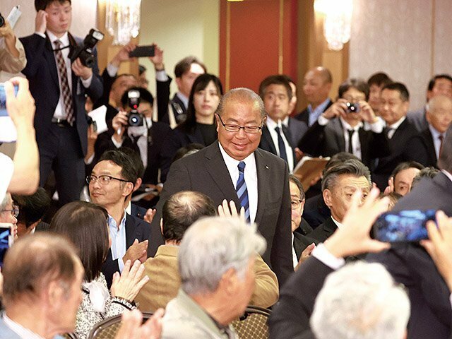 支持者に囲まれて会場入りする新田氏（中央）＝２７日午後８時ごろ、富山市桜橋通りのホテルグランテラス富山