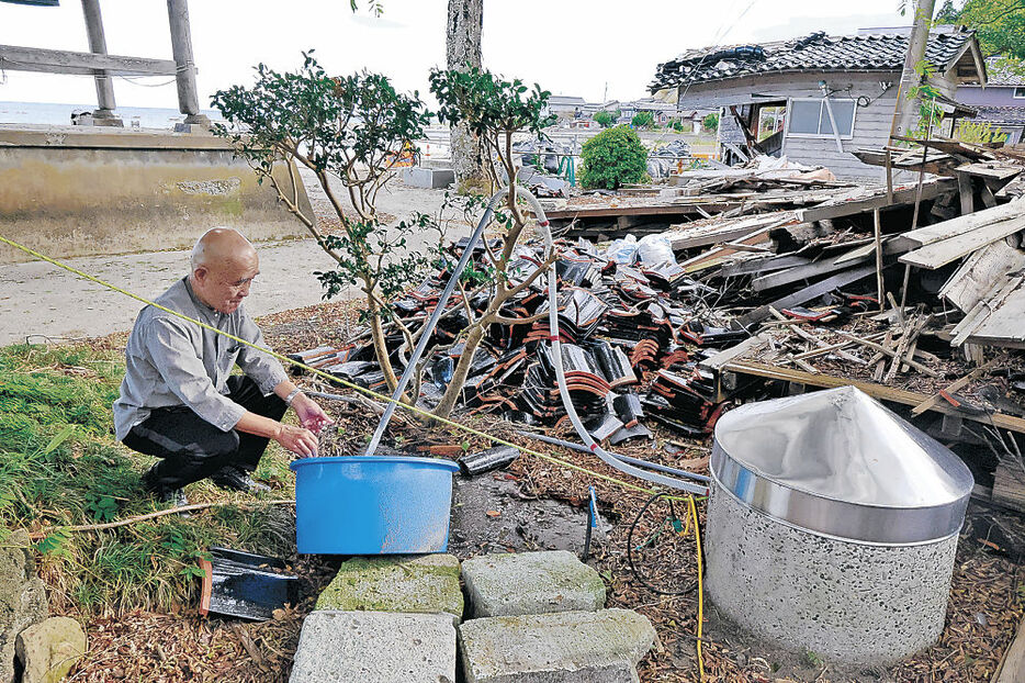 井戸のポンプの動作を確認する畠山住職＝珠洲市三崎町寺家