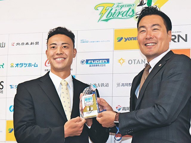 筒井スカウトから藤川監督のサインが入ったドラフト会議の入館証を受け取る佐野（左）＝高岡商工ビル