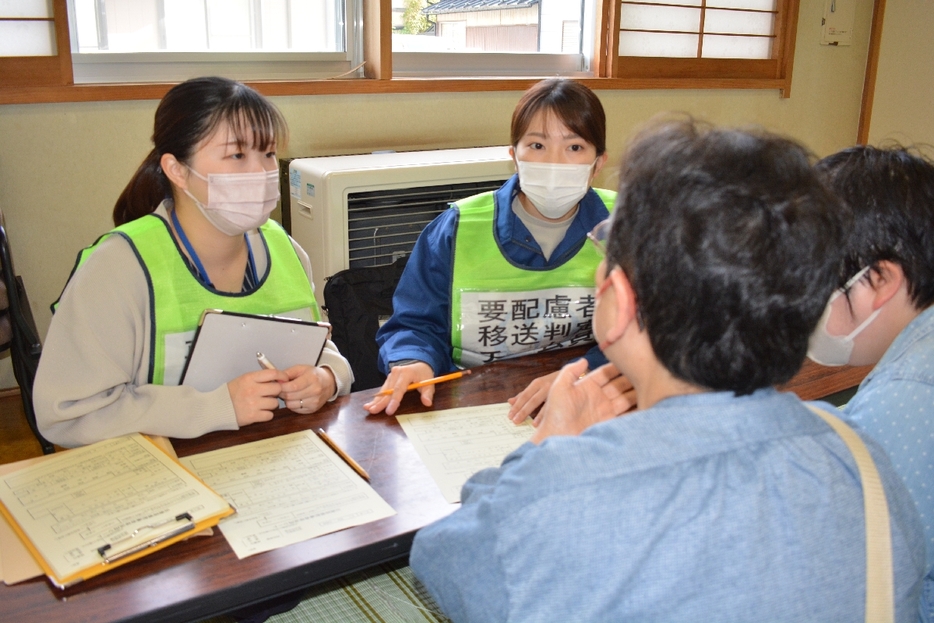 要支援者と保護者から障害の程度などを聞き取り、福祉避難所への移送優先度を判定する八戸市職員＝26日、市立湊公民館