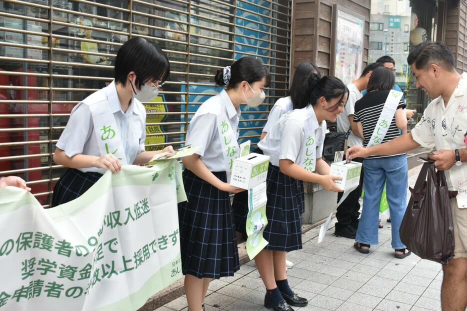 街頭募金を実施するボランティアの高校生ら＝１９日、那覇市牧志の国際通りのれん街前