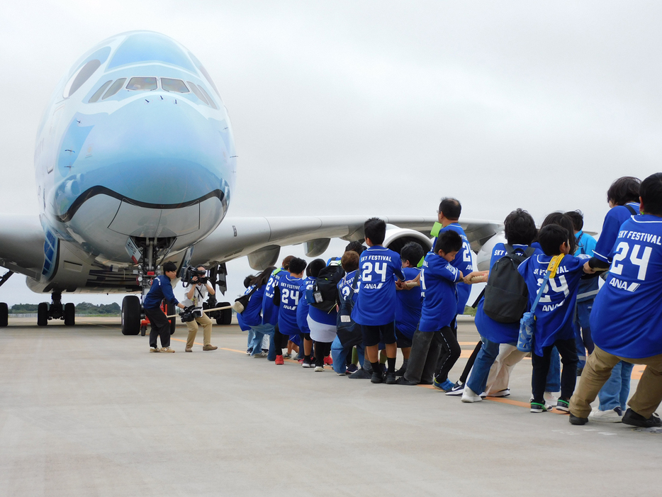 世界最大の旅客機エアバスＡ３８０を引っ張る小学生ら＝６日、千葉県成田市の成田空港