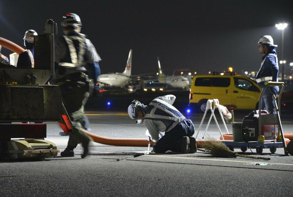 「滑走路状態表示灯（RWSL）」設置の準備をする作業員＝2日未明、羽田空港