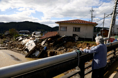 元日の地震で石川県小松市に避難し、９月から輪島市町野町の仮設住宅で暮らす女性（８３）は「本当にひどいね」と氾濫した鈴屋川を眺めていた（２０日）＝桐山弘太撮影