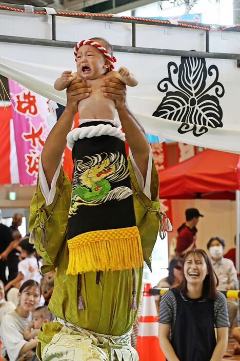 行司役に抱え上げられ、泣き出す赤ちゃん=海陽町の旧海部中学校体育館