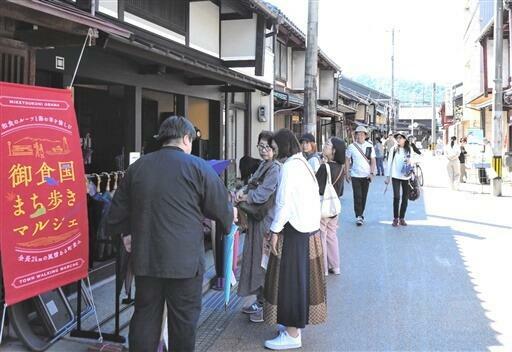 小浜西組周辺エリアをまち歩きし、商品を品定めする観光客=10月13日、福井県小浜市鹿島