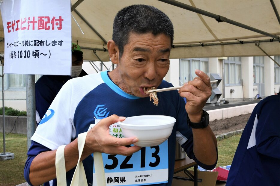 完走後、岩美町特産のモサエビ汁を頬張る選手＝２０日、岩美町浦富の岩美北小