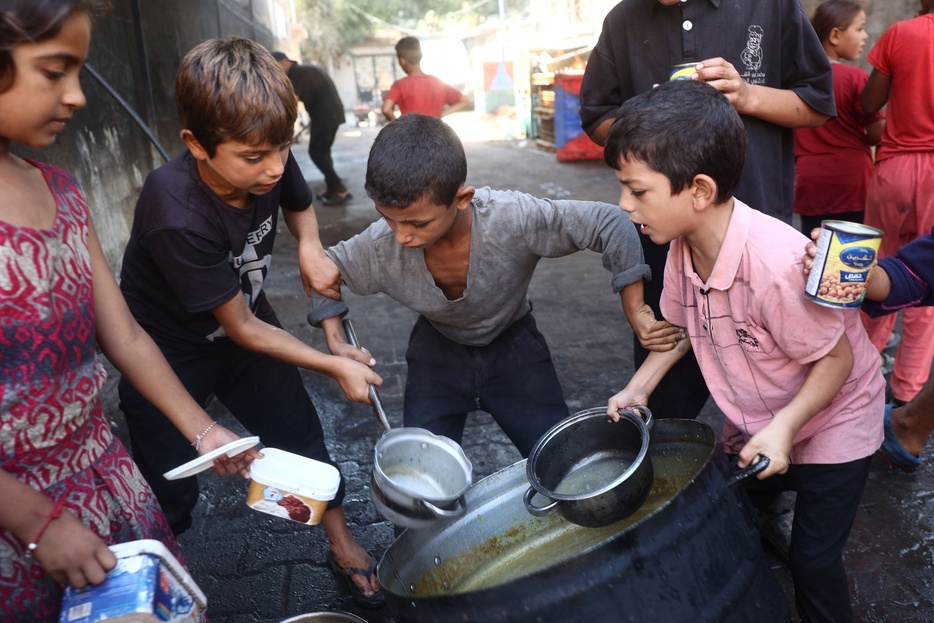 パレスチナ自治区ガザ地区中部デイルアルバラフで、炊き出しの料理を受け取る子どもたち（2024年10月17日撮影）。【翻訳編集】 AFPBB News